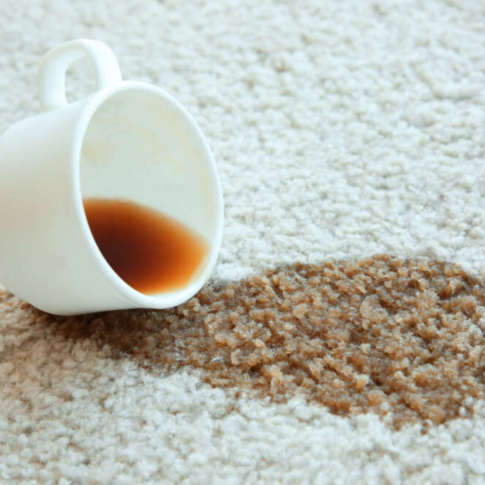 Cup of coffee spilled on white carpet, close up